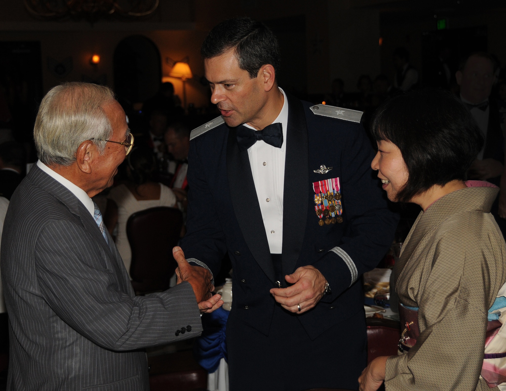 (Center) Brig. Gen. Ken Wilsbach, 18th Wing commander, welcomes Kadena Town Mayor Tokujitsu Miyagi to the Air Force Ball with help from Takako Fukuhara from the 18th Wing public affairs office. Mayor Miyagi was one of several distinguished visitors from the local community to celebrate the Air Force's 63rd birthday. Also in attendance were two generals and a colonel from the Japanese military. (Air Force/A1C Jarvie Wallace)