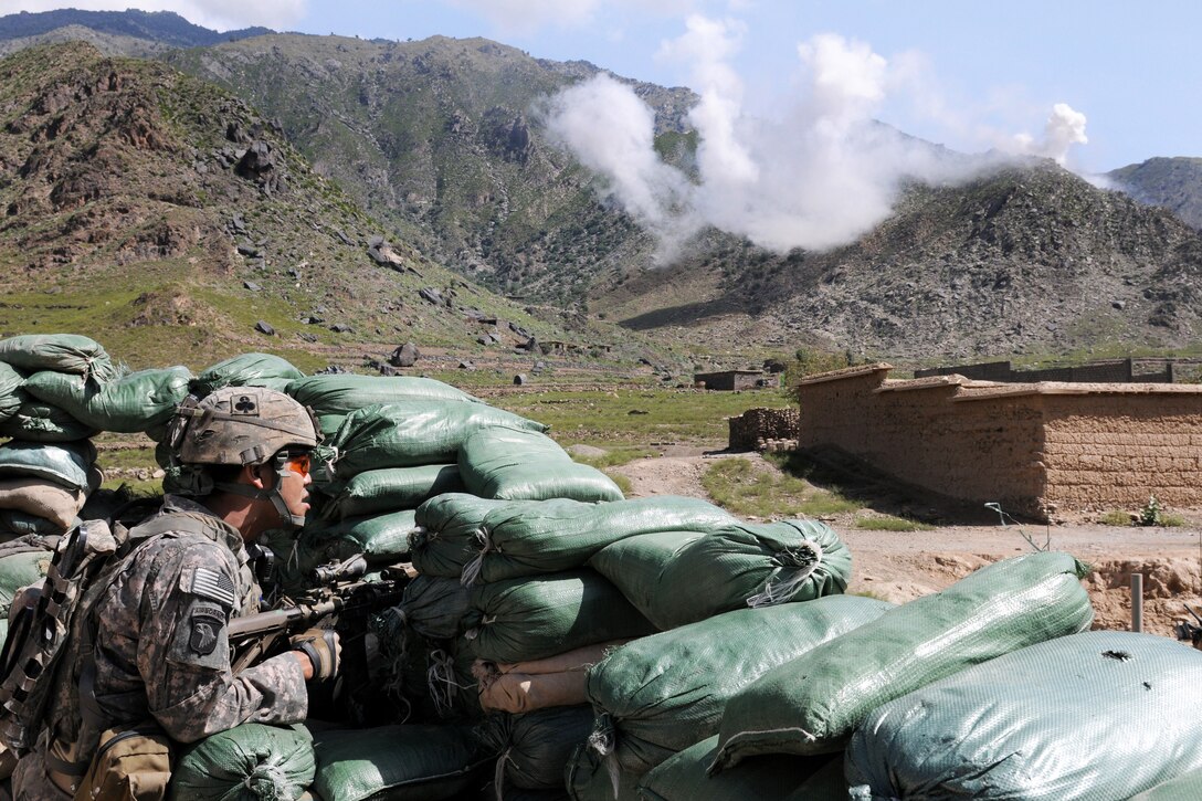 U.S. Army Sgt. Ricardo E. Maya keeps watch as 120mm white phosphorus mortar rounds hit the nearby ridgeline during a firefight at the an Afghan National Police checkpoint in Kunar province, Afghanistan, Sept. 18, 2010. Maya is assigned to the 327th Infantry Regiment's Company D, 1st Battalion, Task Force Bulldog.