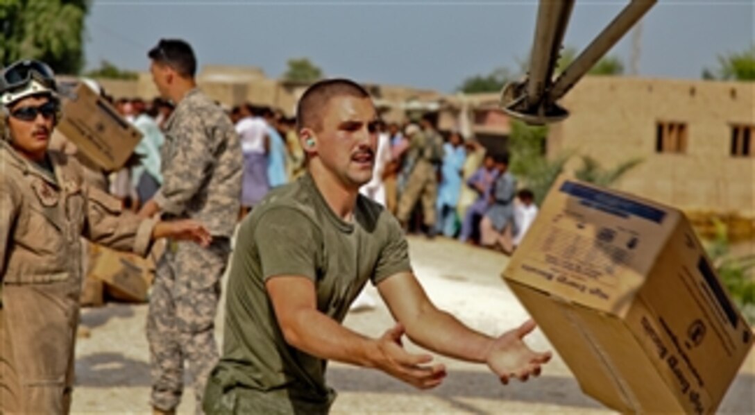 U.S. service members unload food and supplies from a U.S. Marine Corps CH-53E Super Stallion helicopter in support of the Pakistan flood relief effort in Pano Aqil, Pakistan, on Sept. 14, 2010.  