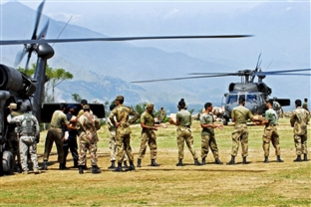 A U.S. Army crew chief watches as Pakistani soldiers load supplies on board a UH-60 Black Hawk helicopter in Rubicon for transport to flood-affected areas in Swat Valley, Khyber Pakhtunkhwa region, Pakistan, Sept. 19, 2010.