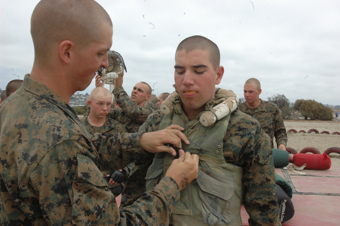 Recruit Andrew O’Shoughnessy, left, Platoon 2106, Company E, 2nd Recruit Training Battalion, snaps the buttons down on the flak jacket of Rct. Eric Rueseler, right, Platoon 2106, Co. E. 2nd Recruit Training Bn.
