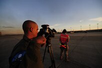 Staff Sgt. Nyx Nieves-Lopez, left, documents a C-130 Hercules crew chief  from the 2nd Airlift Squadron at Pope AFB, N.C., as he stands ready to marshal his aircraft for a launch during a joint forcible entry exercise Sept. 14, 2010. JFEXs are training events held six times a year to enhance cohesiveness between the Air Force and Army by executing large-scale heavy equipment and troop movements for real world contingencies. Sergeant Nieves-Lopez is a videographer assigned to the 1st Combat Camera Squadron. (U.S. Air Force photo by Tech. Sgt. DeNoris A. Mickle/Released)