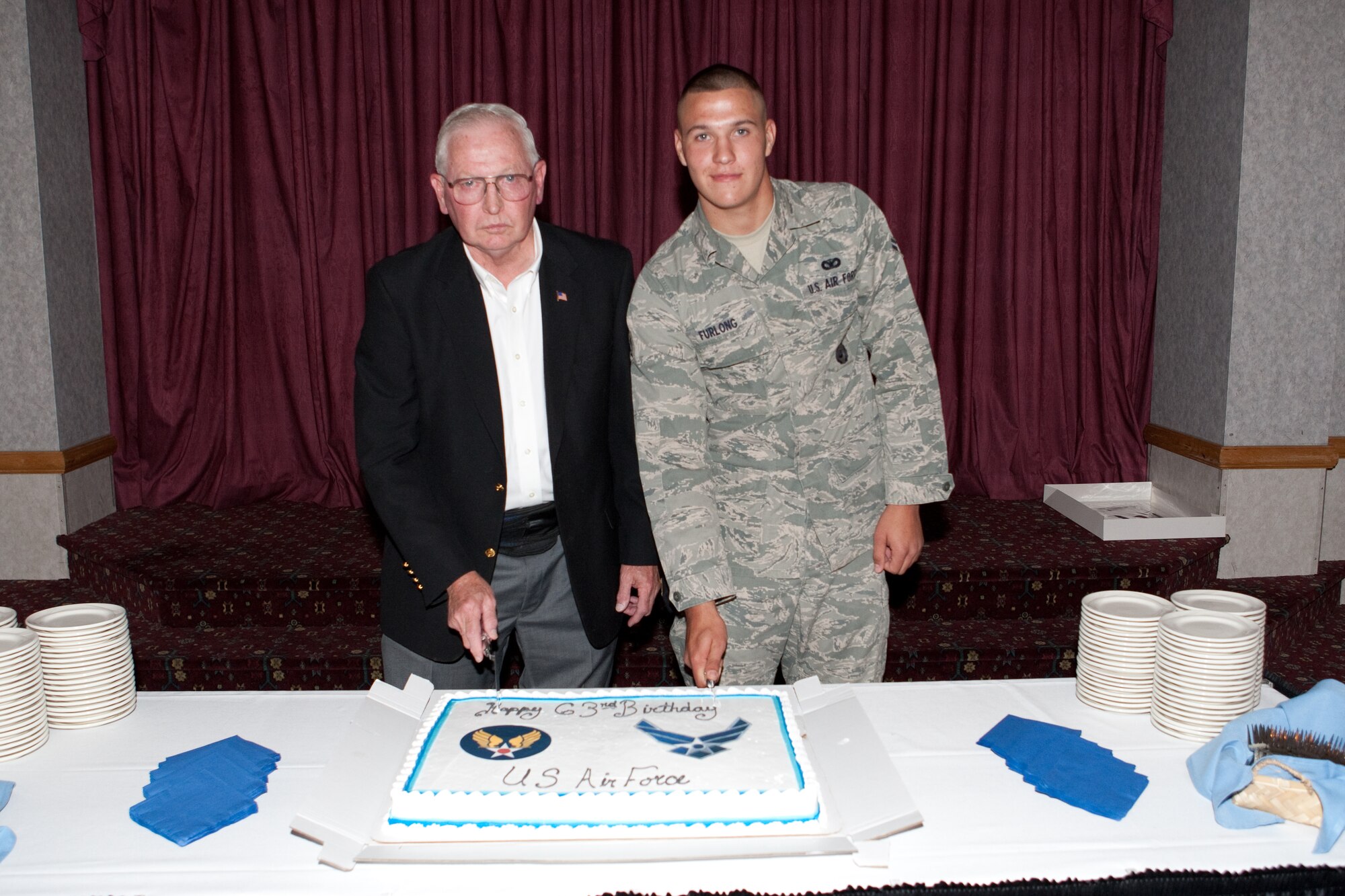 Col. (ret) Chuck Blackburn and Airman 1st Class Richard Furlong, 90th Missile Security Forces Squadron, the most seasoned representative and most junior on base respectively cut the cake to help celebrate the Air Force’s 63rd birthday at the Trail’s End Club here on Sept. 17. Attendants to the party enjoyed cake and punch along with a slide show of photos taken around base. (U.S. Air Force photo by Jeff Allred)
