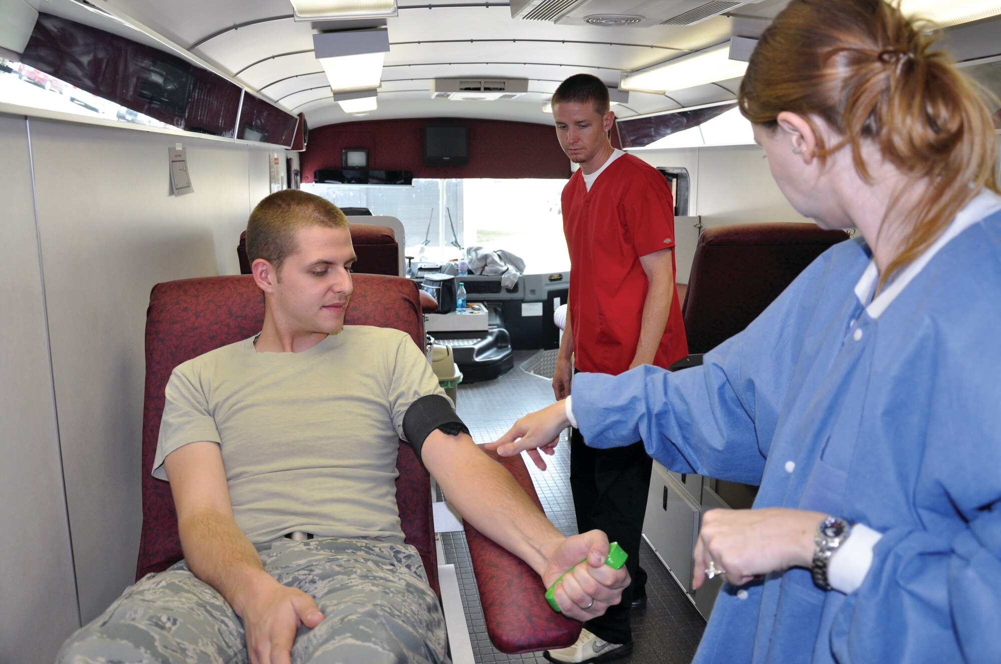 Airman 1st Class Paul Link, 90th MDOS, flexes his arm to expose his veins for Jason Cooney and Kendra Stenner, both Donor Care Specialists on the United Blood Services bus, during the 90th medical groups blood drive on Sept. 8. (U.S. photo by Airman 1st Class Dan Gage)