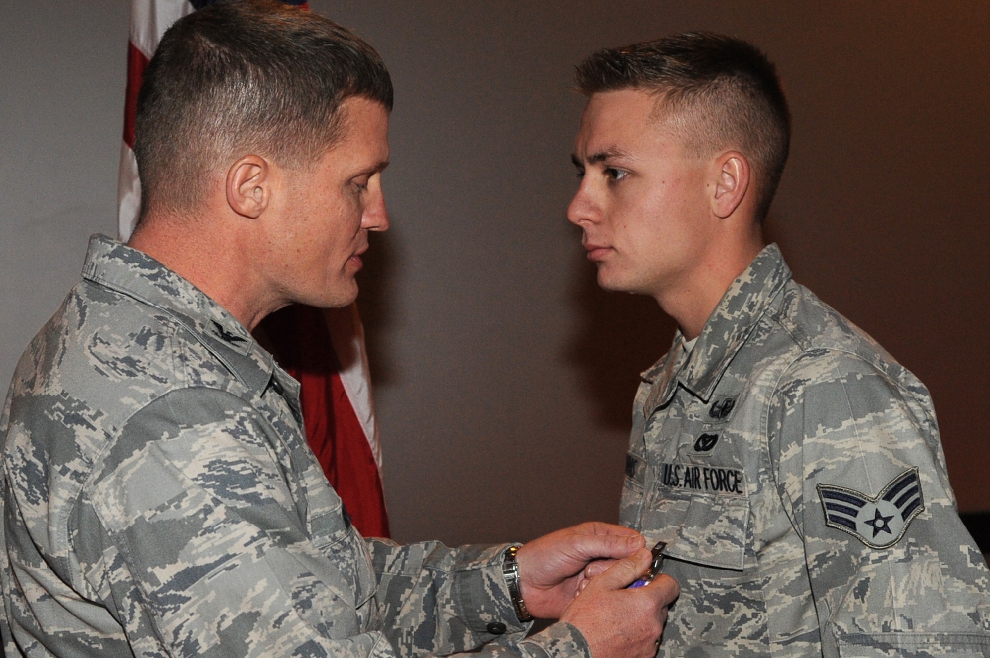 Retired Col. Dave Belote, former 99th Air Base Wing commander, presents the Purple Heart to Senior Airman Michael Buras, 99th Civil Engineer Squadron explosive ordnance disposal journeyman, at the Nellis Theater during a commander's call Dec. 4, 2009.  Airman Buras died Sept. 21 of wounds suffered as the result of an improvised explosive device detonation in Kandahar, Afghanistan. (U.S. Air Force photo by Lawrence Crespo)
