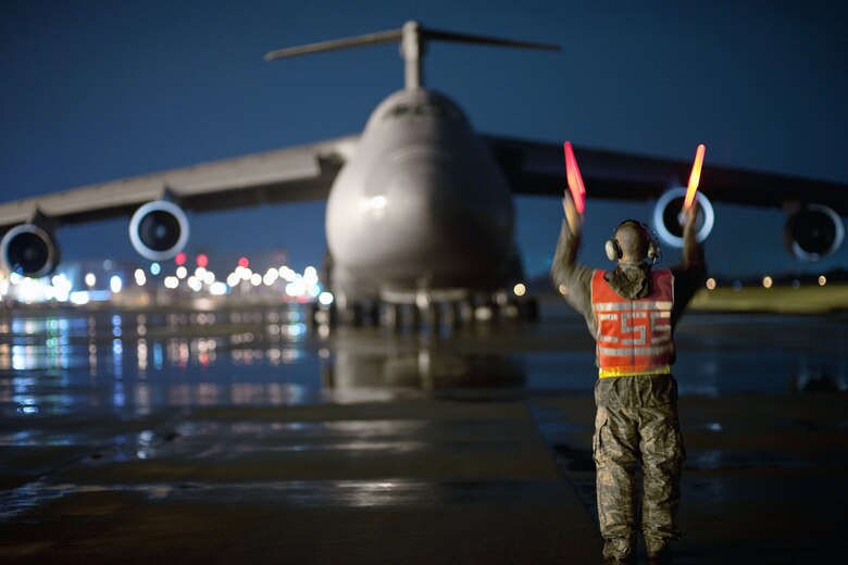 Staff Sgt. Dustin McComas marshals a C-5 Galaxy Sept. 15, 2010, after it lands at Yokota Air Base, Japan.  Sergeant McComas is a loadmaster with the 730th Air Mobility Squadron there.  (U.S. Air Force photo/Osakabe Yasuo)