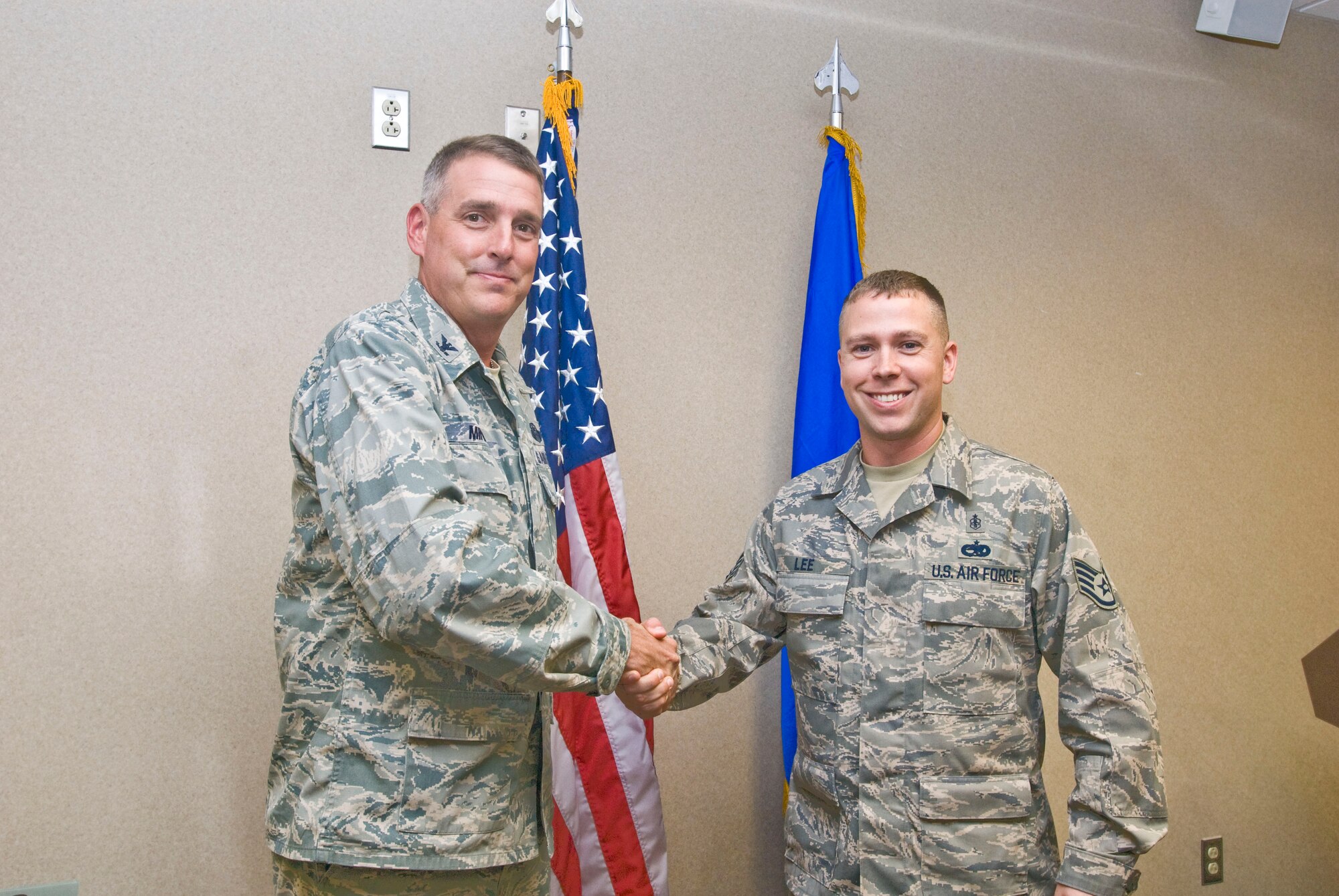 Col. Mike Minihan (left), 19th Airlift Wing commander, presents a coin Sept. 20 to Staff Sgt. Samuel Lee, 19th Medical Operations Squadron mental health clinic NCO-in-charge, for his selection as the Combat Airlifter of the Week. Sergeant Lee completed approximately 1,089 appointments this past month, caring for 6,500 Airmen. (U.S. Air Force photo by Staff Sgt. Nestor Cruz)