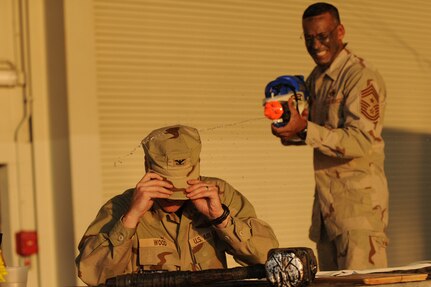 Chief Master Sgt. Terrence Greene sprays Col. John Wood with a water gun during the opening of the combat dining out on Joint Base Charleston, S.C., Sept. 17, 2010. The soaking continued throughout the evening as Airmen were pitted against each other. Colonel Wood is the 437th Airlift Wing commander and Chief Greene is the 437 AW command chief.  (U.S. Air Force photo/James M. Bowman)(Released)