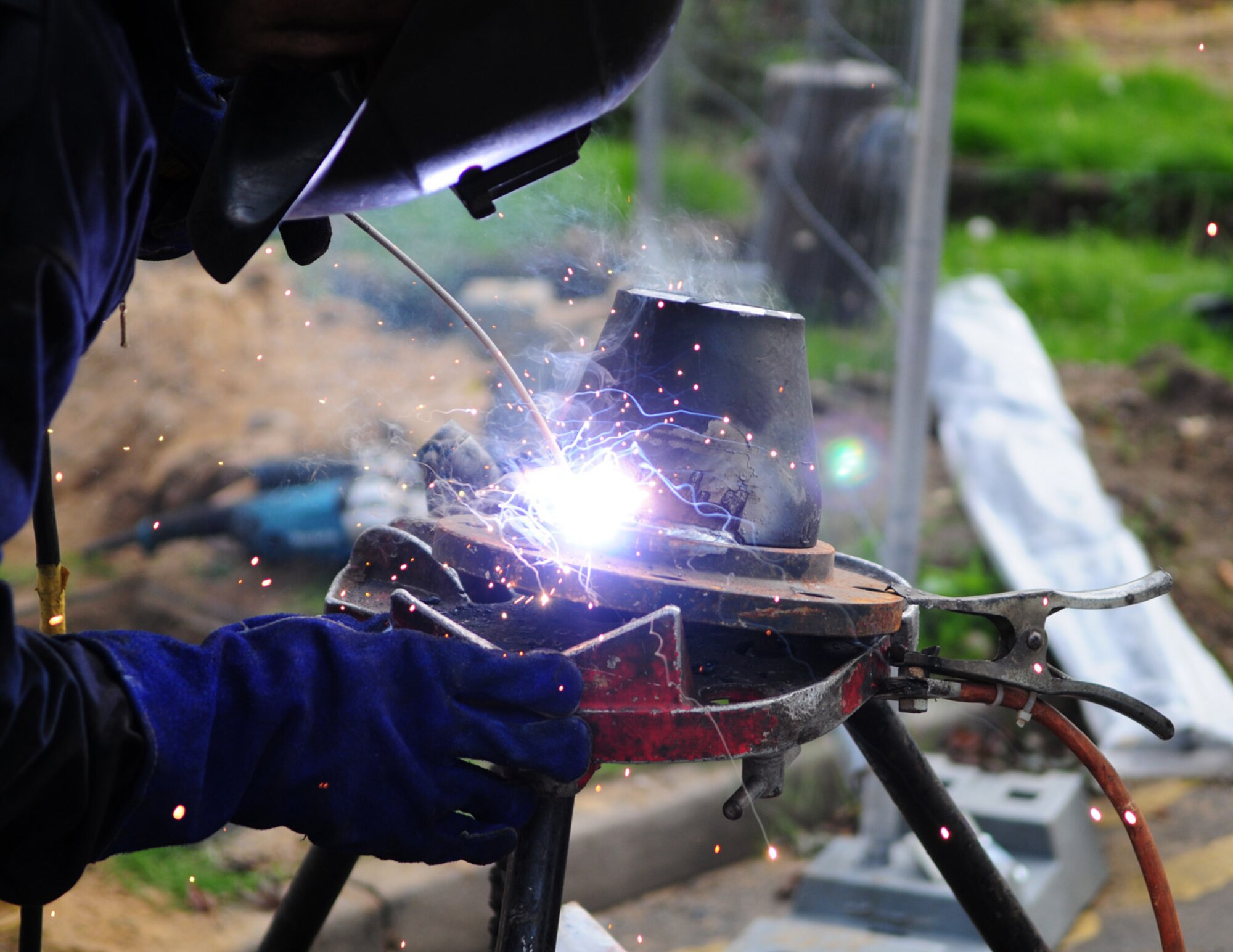 RAF MILDENHALL, England -- Paul Blackbird, a local contractor, uses a welder and welding rod on 6-inch steel pipe Sept. 22. Once the welding is finished, the metal pipe will be used to complete a circuit and link the district heating main back to the boiler house. The heating pipes originally led to old domitories, which are  being demolished. (U.S. Air Force photo/Karen Abeyasekere)