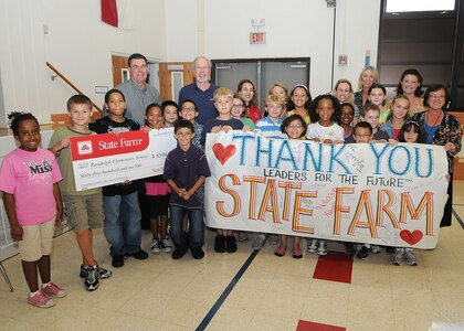 Elementary school students at Randolph Air Force Base, Texas, display a sign thanking State Farm Insurance on Sept 21, after receiving a grant for $6,500 to fund leadership training at the school. An enlarged check, left, is held up by the 4th and 5th grade students, who are dependants of active duty military stationed at the base.  As part of their "Leaders for the Future" training, the students have put together outlines to improve their educational experience.  (U.S. Air Force photo/David Terry)