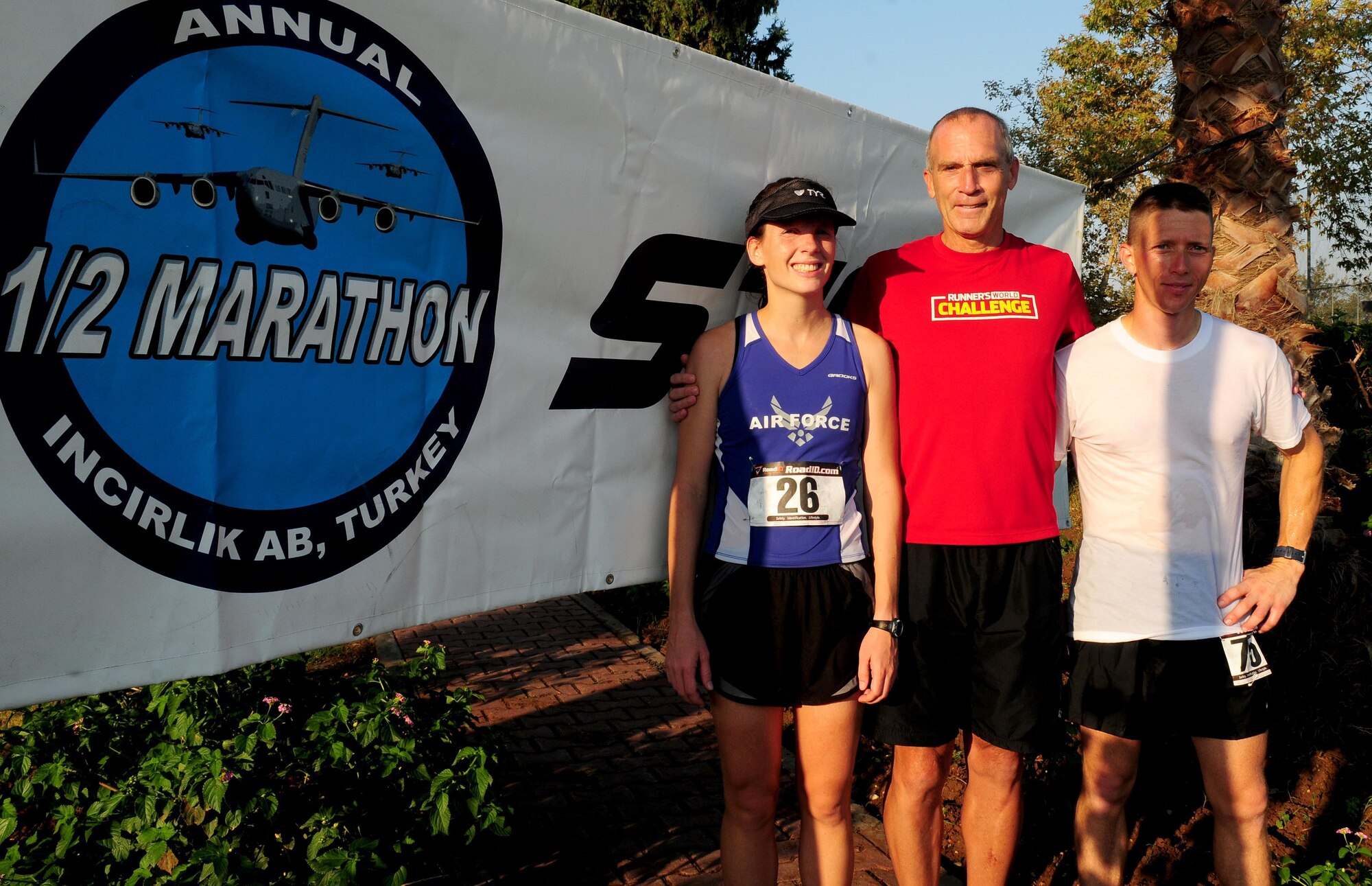 Top female and male marathon runners Elissa Ballas (left), 39th Medical Operations Squadron, and William Chapman (right), 90th Expeditionary Air Refueling Squadron have their photo taken with Bart Yasso, chief running officer of Runner’s World Magazine, Sept. 18, 2010.  Chapman came in first place in the males 29 and under category with a run time of 1 hour 22 minutes and 32 seconds and Ballas came in first place in the females 30 and over category with a run time of 1:22:58.  (U.S. Air Force photo by Senior Airman Ashley Wood/Released)