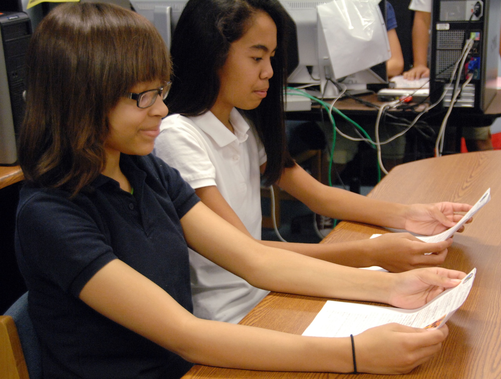 Anchors, Alyssa McGillvery and Gwen Europa, 8th grade students at Andersen Middle School, practice reading their lines prior to the live broadcast of KAMS-TV news. Each morning a group of AMS students from various grades combine their skills to produce a morning show for the student body featuring news, sports and various announcements. (U.S. Air Force photo by Airman Whitney Amstutz)