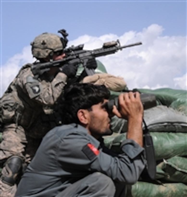 U.S. Army Pfc. Ryan L. Carson, a member of the company intelligence support team of Alpha Company, 1st Battalion, 327th Infantry Regiment, Task Force Bulldog, and an Afghan police officer search a hillside at the Shege East Afghan National Police Checkpoint in the Kunar province of Afghanistan prior to a firefight on Sept. 18, 2010.  Approximately two dozen insurgents fired rocket-propelled grenades, heavy machine guns and small arms at the post.  International Security Assistance Forces and Afghan National Police responded with small arms, heavy machine gun and mortar fire.  