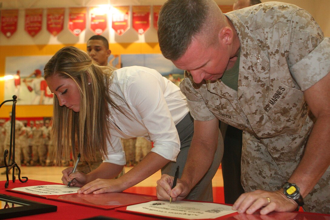 Col. Eric M. Smith, the commanding officer for 8th Marine Regiment, and Tayler Snipes, the student government president for Camp Lejeune High School, sign the Adopt a School argreements officially pairing school with 8th Marine Regiment.  The Marines will provide short clinics to sports teams, provide tutors for academic classes, bring logistical support for the Spring field meet, assist in graduation  preparations and support school improvement projects throughout the year.::r::::n::