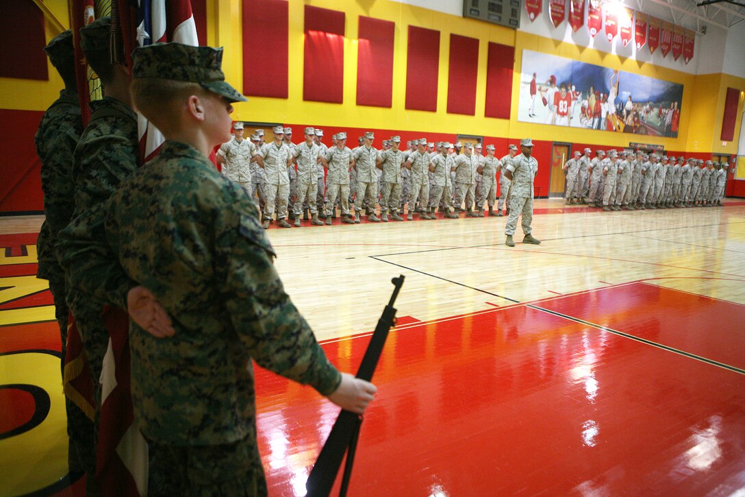 Marines from Headquarters Company, 8th Marine Regiment, and the Marine Corps Junior ROTC Color Guard stand in formation during the Adopt a School ceremony at Camp Lejeune High School Sept. 23.  The Marines will partner with the school to assist with projects throughout the school year.