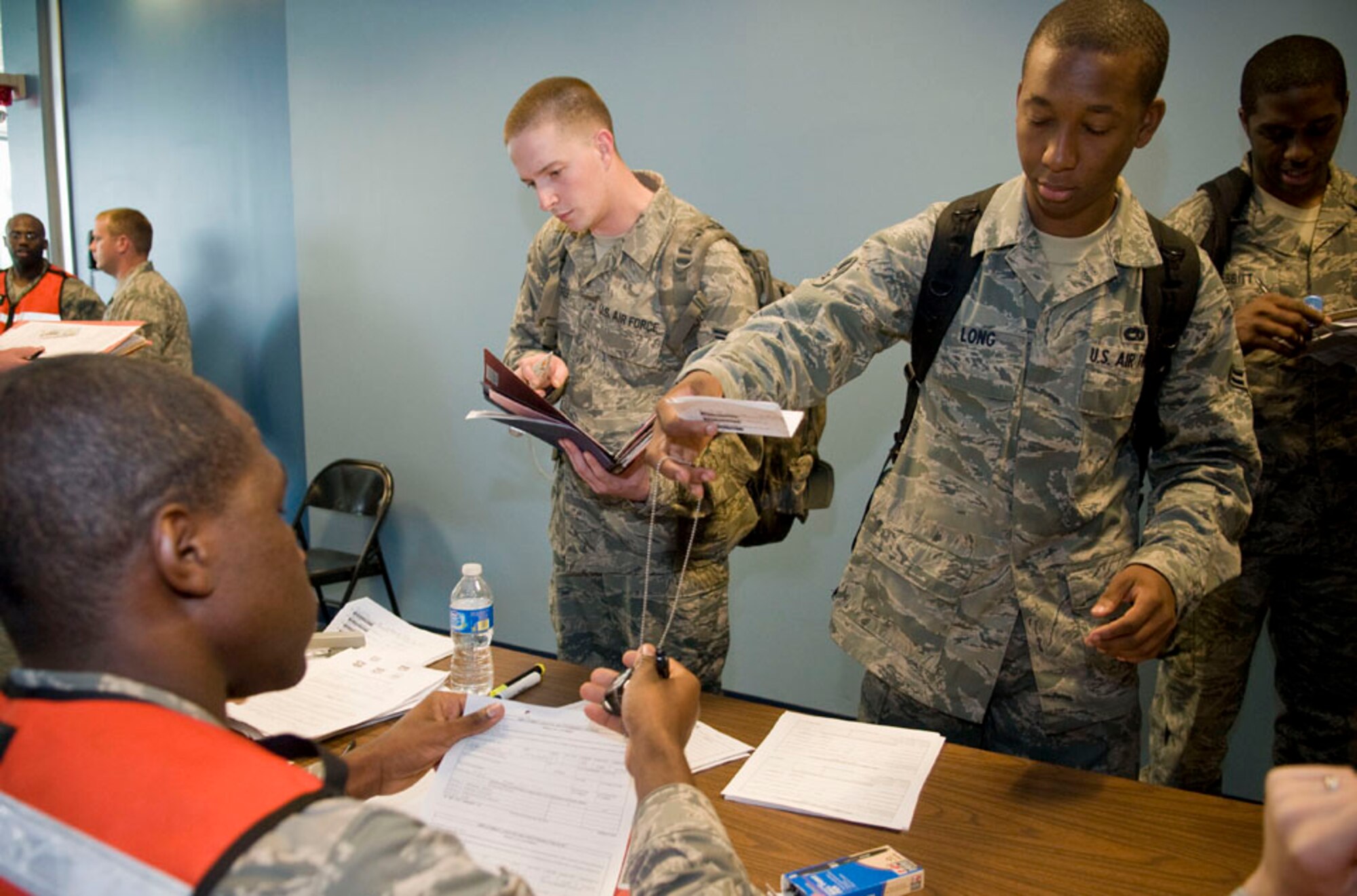 Airman 1st Class Trevaris Long, 35th Aircraft Maintenance Squadron, hands identification tags to Airman 1st Class Shanon Oge, 35th Force Support Squadron, during a Misawa Air Base, Japan, personnel deployment function line, Sept. 23, 2010. Supporting base agencies, such as public health, finance, and legal helped Airmen finalize their deployment checklists by providing their respective services. (U.S. Air Force photo by Senior Airman Jessica Lockoski/Released)