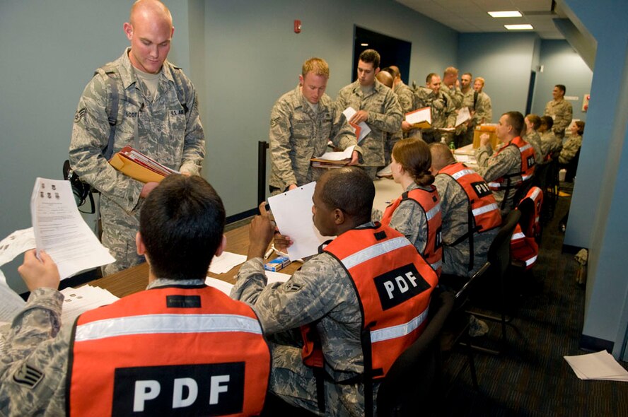Senior Airmen Derek Scott, 35th Aircraft Maintenance Squadron, gives his deployment out-processing checklist to Airmen working a Misawa Air Base, Japan, personnel deployment function line, Sept. 23, 2010. Airmen processed through the deployment line for squadron deployment in support of Operation New Dawn. (U.S. Air Force photo by Senior Airman Jessica Lockoski/Released)