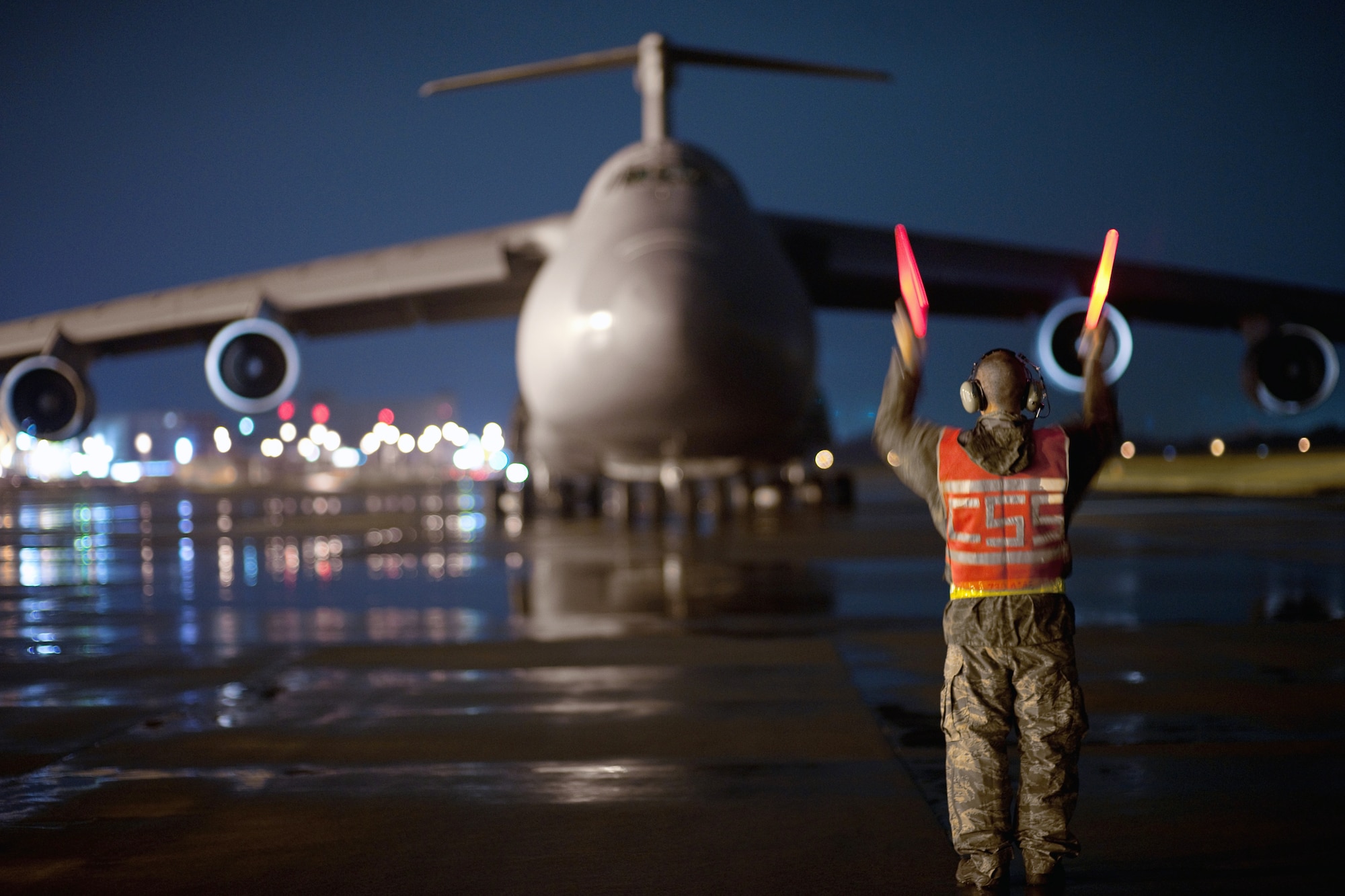 Staff Sgt. Dustin McComas, 730th Air Mobility Squadron, marshals a C-5 Galaxy aircraft after it lands at Yokota Air Base, Japan, Sept. 15, 2010. Yokota Airmen work 24/7 operations to keep inbound and outbound aircraft running in the airlift hub of the western Pacific. (U.S. Air Force photo/Osakabe Yasuo)