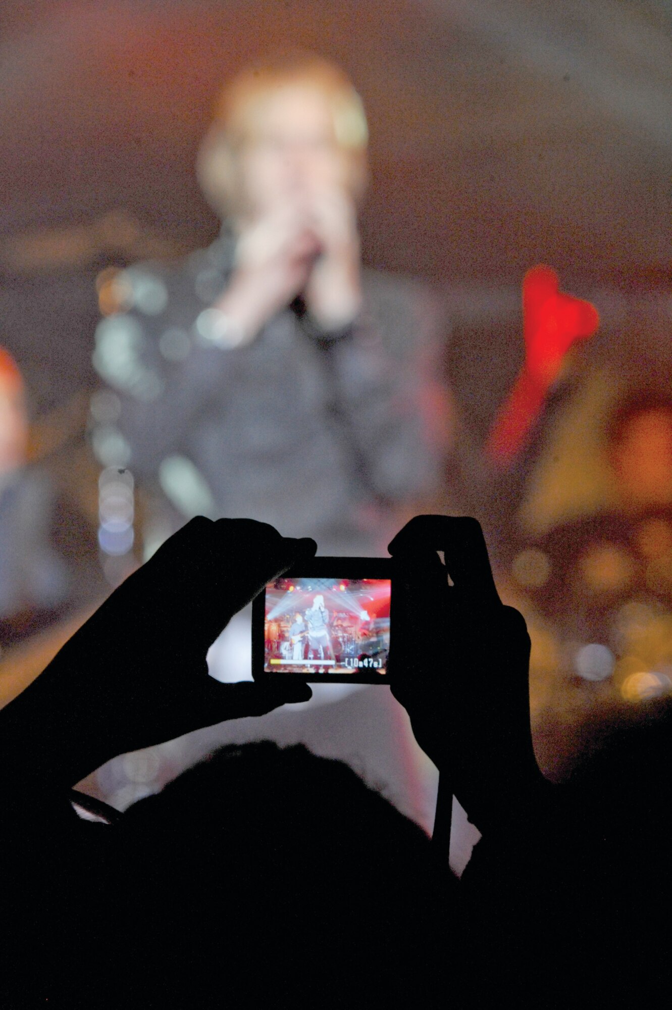 An audience member takes a photo of vocalist Dan Myers, of the Lieutenant Dan Band, during their performance for service members and their families here, Sept. 16. The band entertained the audience with cover songs for more than an hour and a half. (Photo by Air Force Staff Sgt. Joshua Garcia/JBER PAO)