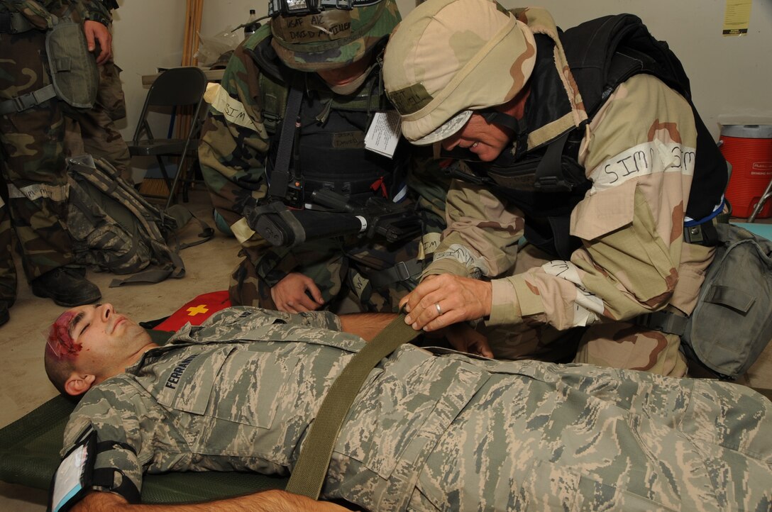 ELLSWORTH AIR FORCE BASE, S.D. -- (Left to right) Airman 1st Class David McMillen, 28th Civil Engineer Squadron, heating, ventilation and air-conditioning apprentice and Master Sgt. Lee Greenwell, 28 CES water and fuels systems craftsman, secure a simulated patient to a stretcher during a Phase II Operational Readiness Exercise, Sept. 16.  Airmen are tested on their skills in self-aid buddy care during the exercise. (U.S. Air Force photo/Airman 1st Class Anthony Sanchelli)
