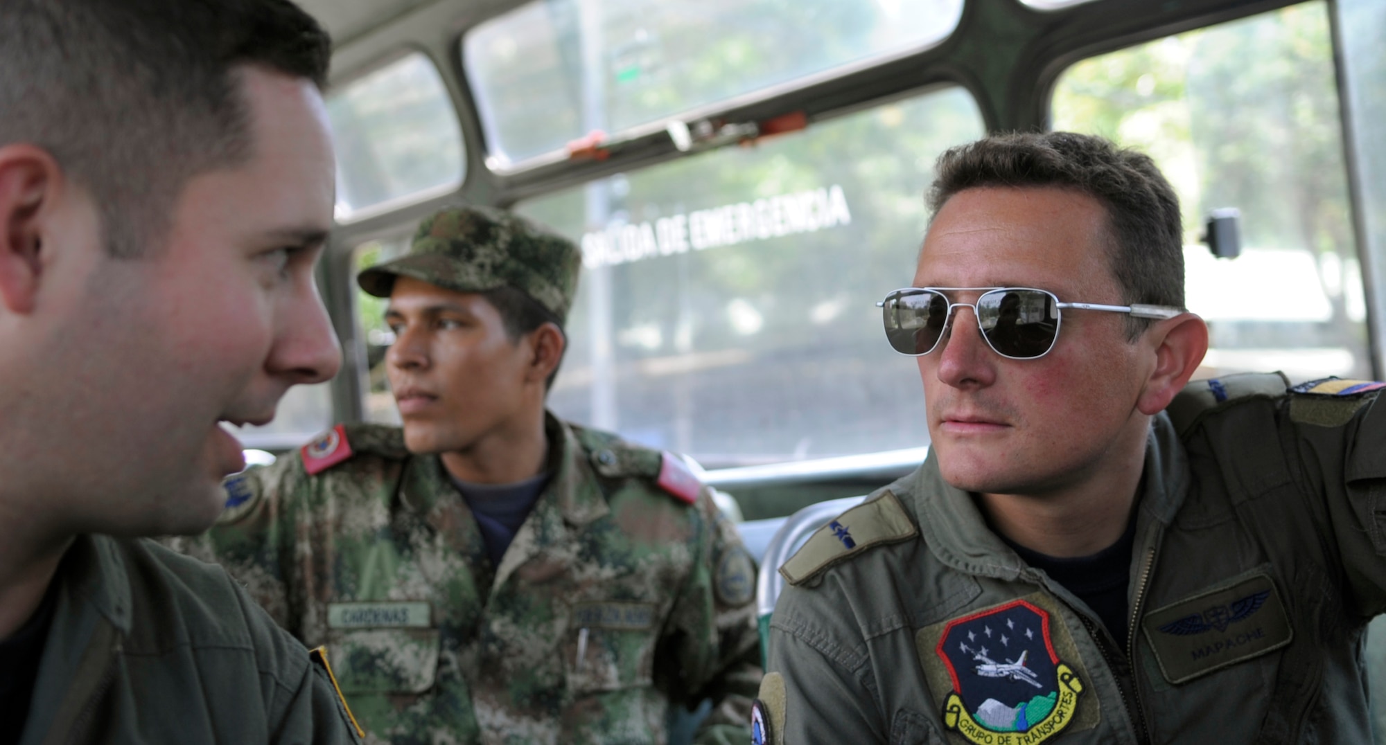 PALANQUERO AIR BASE, Colombia -- Mayor (Maj.) Eduardo ‘Mapache’ Restrepo, (right) Colombian air force C-130 co-pilot, talks to U.S. Air Force C-130 navigator Capt. Ramon Fierros about the day’s upcoming mission while riding a bus to a crew brief Sept. 16 here.  