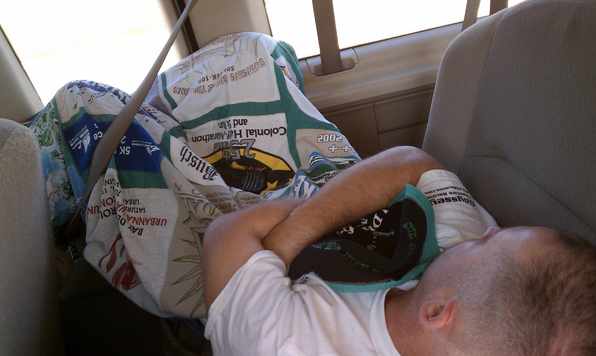 Capt. Chris Woofter cuddles up under the quilt his mother made him from race shirts while on a 12-hour ride to the 2010 Air Force Marathon in Dayton. (USAF photo by MSgt. Wendy Lopedote, 916ARW/PA)