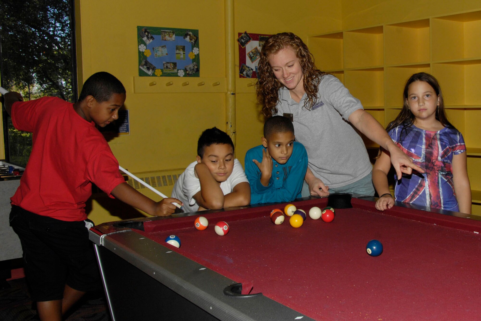 HANSCOM AIR FORCE BASE, Mass. – Ann-Marie Ely (second from right) teaches children how to play pool during an afternoon  sports club at the Hanscom Youth Center. Ms. Ely was the first youth center employee at Hanscom to earn a Youth Development Credential and was among the first group of Air Force Youth Center employees to gain this recognition. (U.S. Air Force photo by Linda LaBonte Britt)