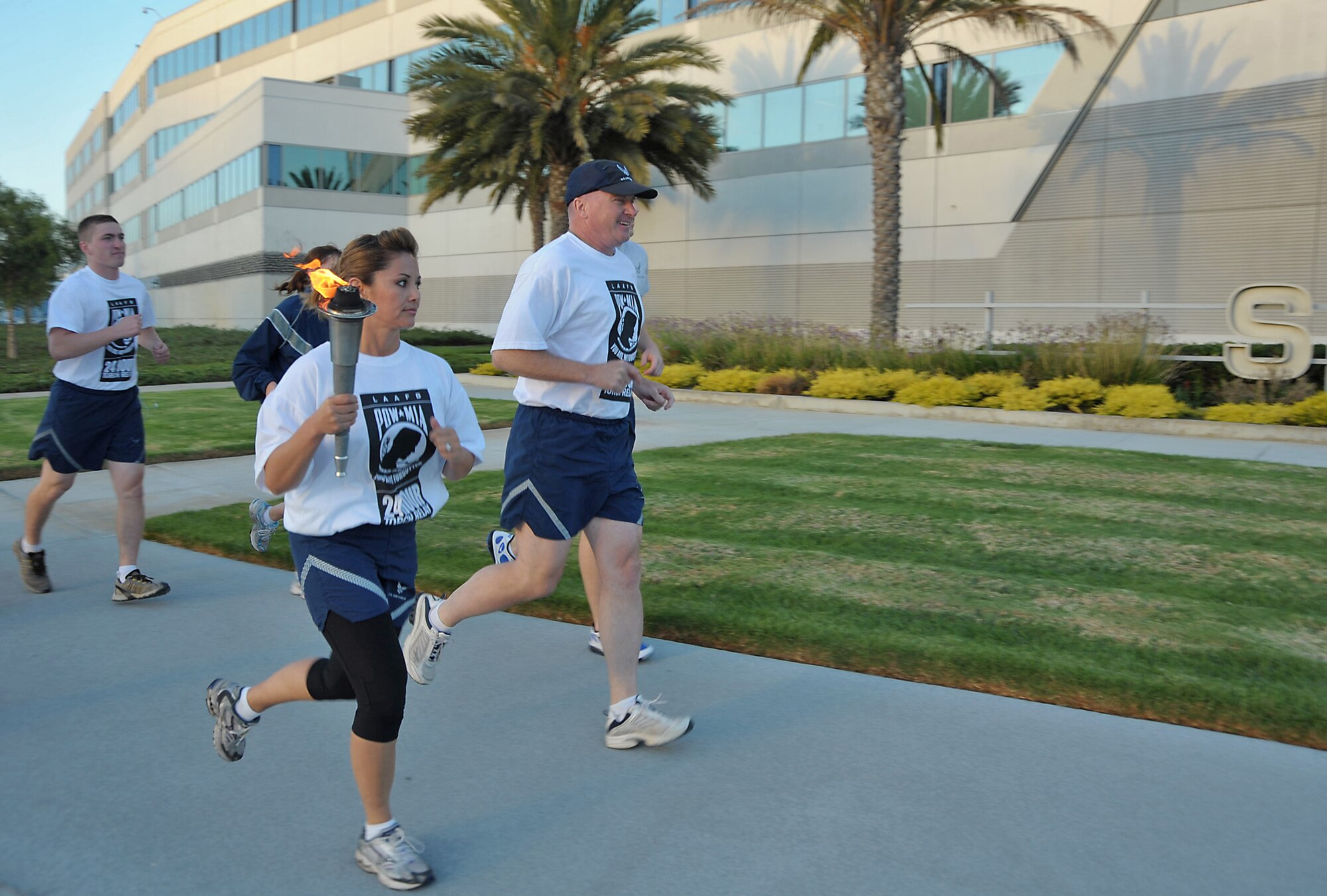 Runners carry the torch around the Los Angeles AFB track during the 24-hour POW-MIA relay, Sept 16. (Photo by Joe Juarez)