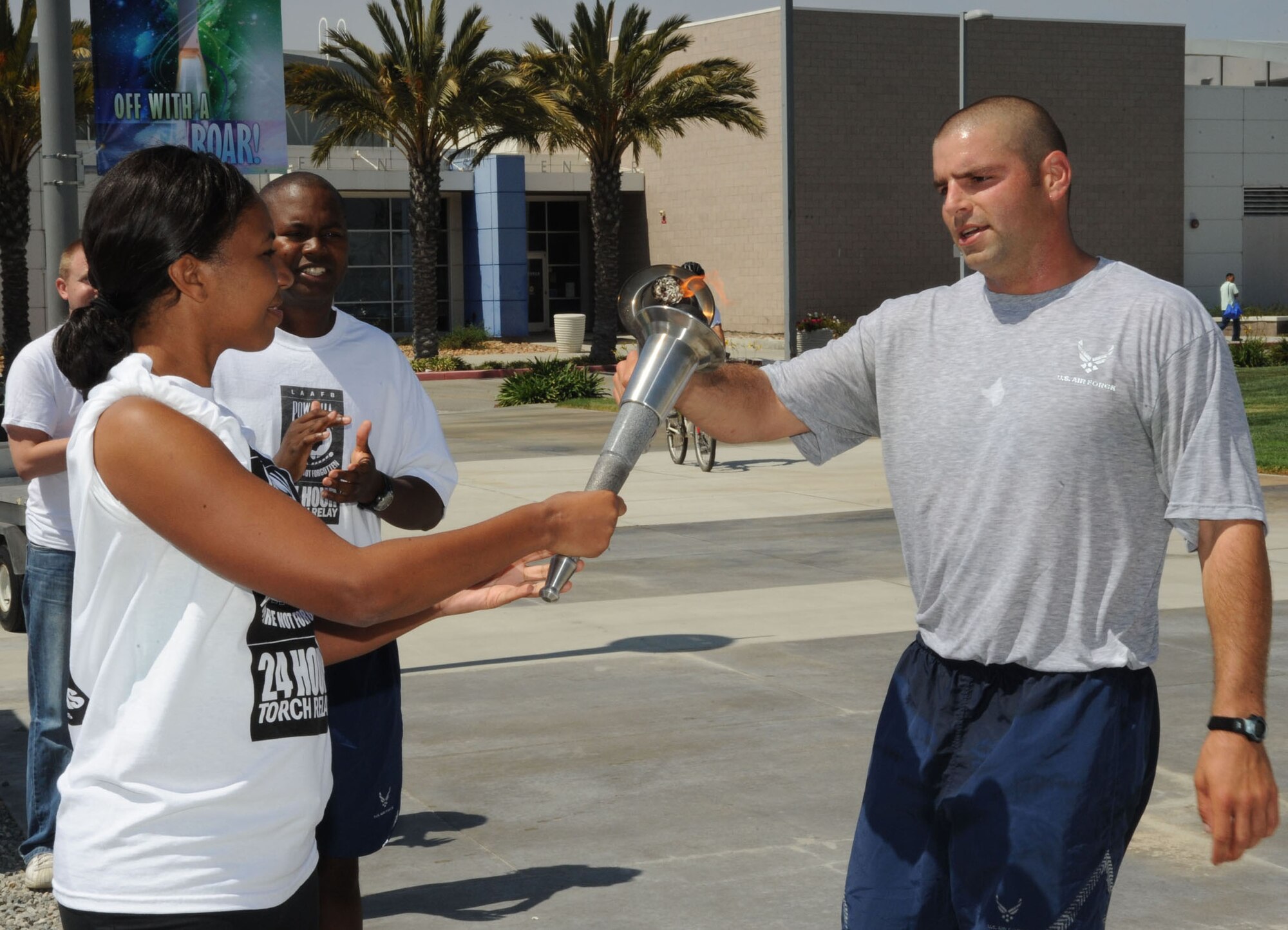 Lt.  Grant Thomas passes the torch to Tiffney West during the 24-hour POW-MIA relay, Sept. 16 . (Photo by Lou Hernandez)