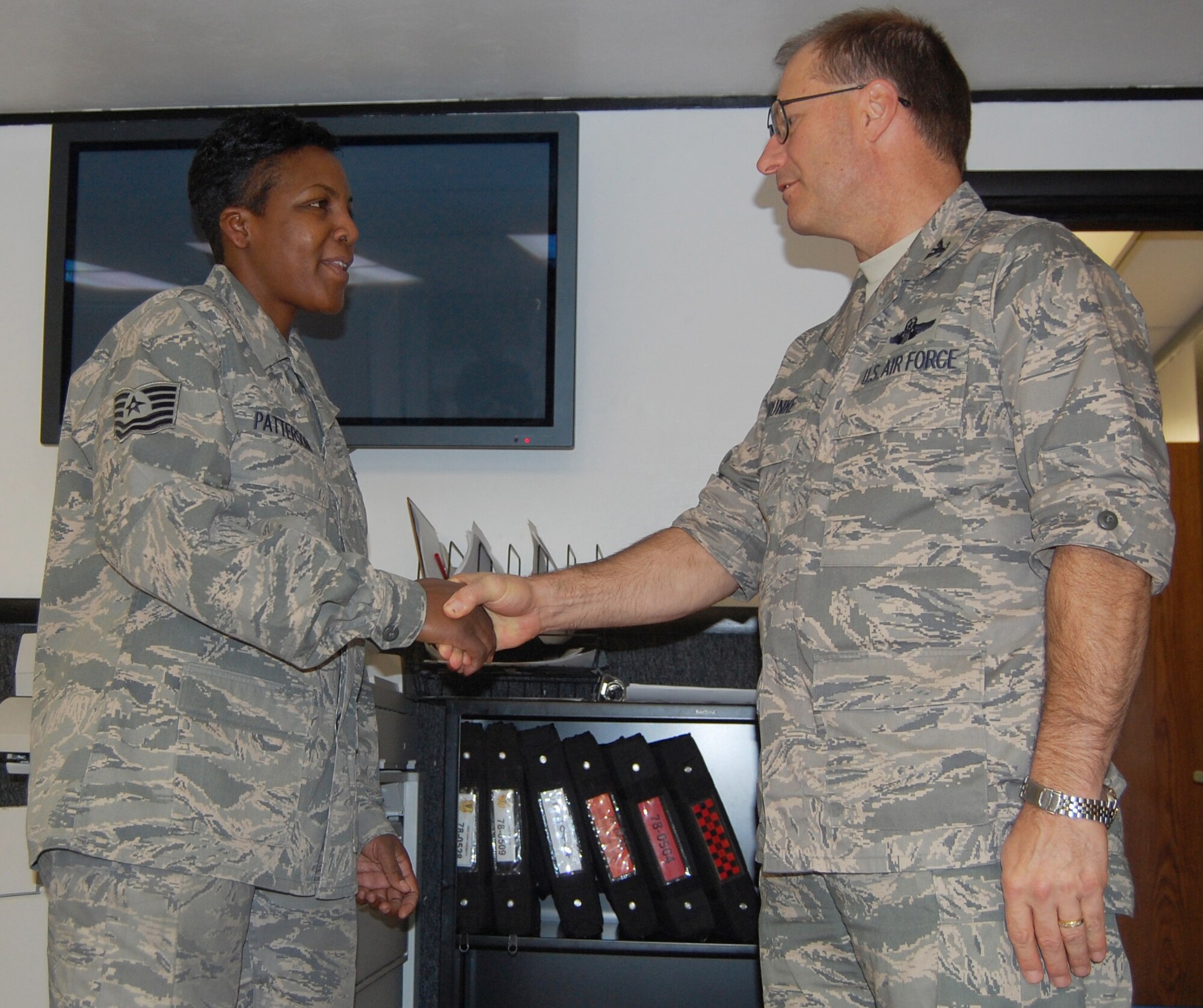 Col. Brunke (right), 926th Group commander, coins Tech. Sgt. Patterson for a "job well done" during a recent dissimilar air combat training, or DACT, exercise that took place in Holloman Air Force Base, N.M. Sergeant Patterson, an Active Guard and Reserve member, is an expeditor with the 926th Aircraft Maintenance Squadron. Through the Air Force's Total Force Integration initiative, she's also integrated as an expeditor in the Flanker Aircraft Maintenance Unit, a Regular Air Force unit here.