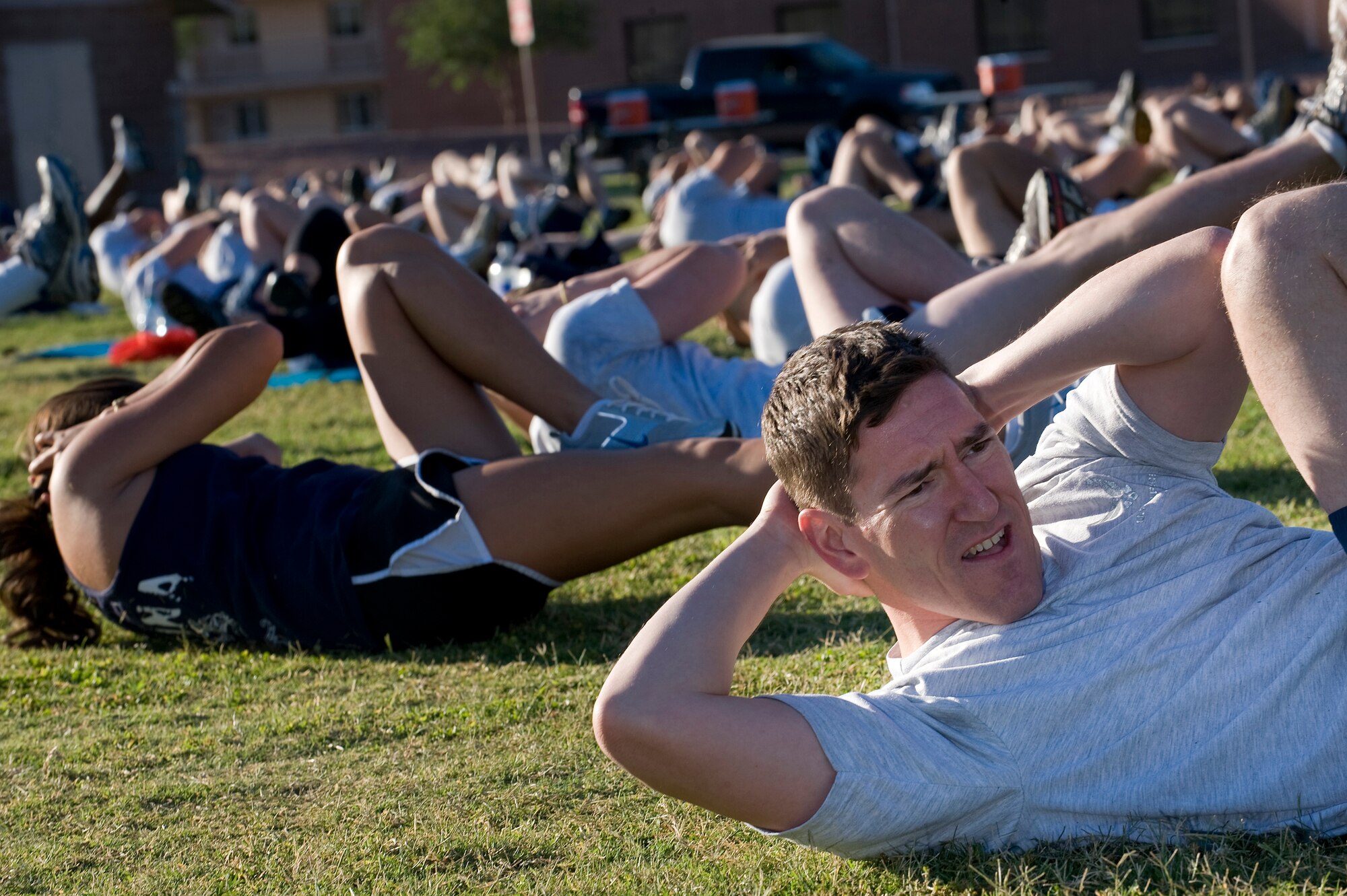 NELLIS AIR FORCE BASE, Nev.-- Lt. Col. Jeff Lewis, a surgeon assigned to the 99th Medical Group, performs a bicycle-crunch exercise with other Airmen during a workout led by fitness trainer Tony Horton at the Nellis Sports Pavilion, Sept. 24. Mr. Horton developed a fitness system which is used by military members from around the world. (U.S. Air Force photo by Senior Airman Brett Clashman/Released)
