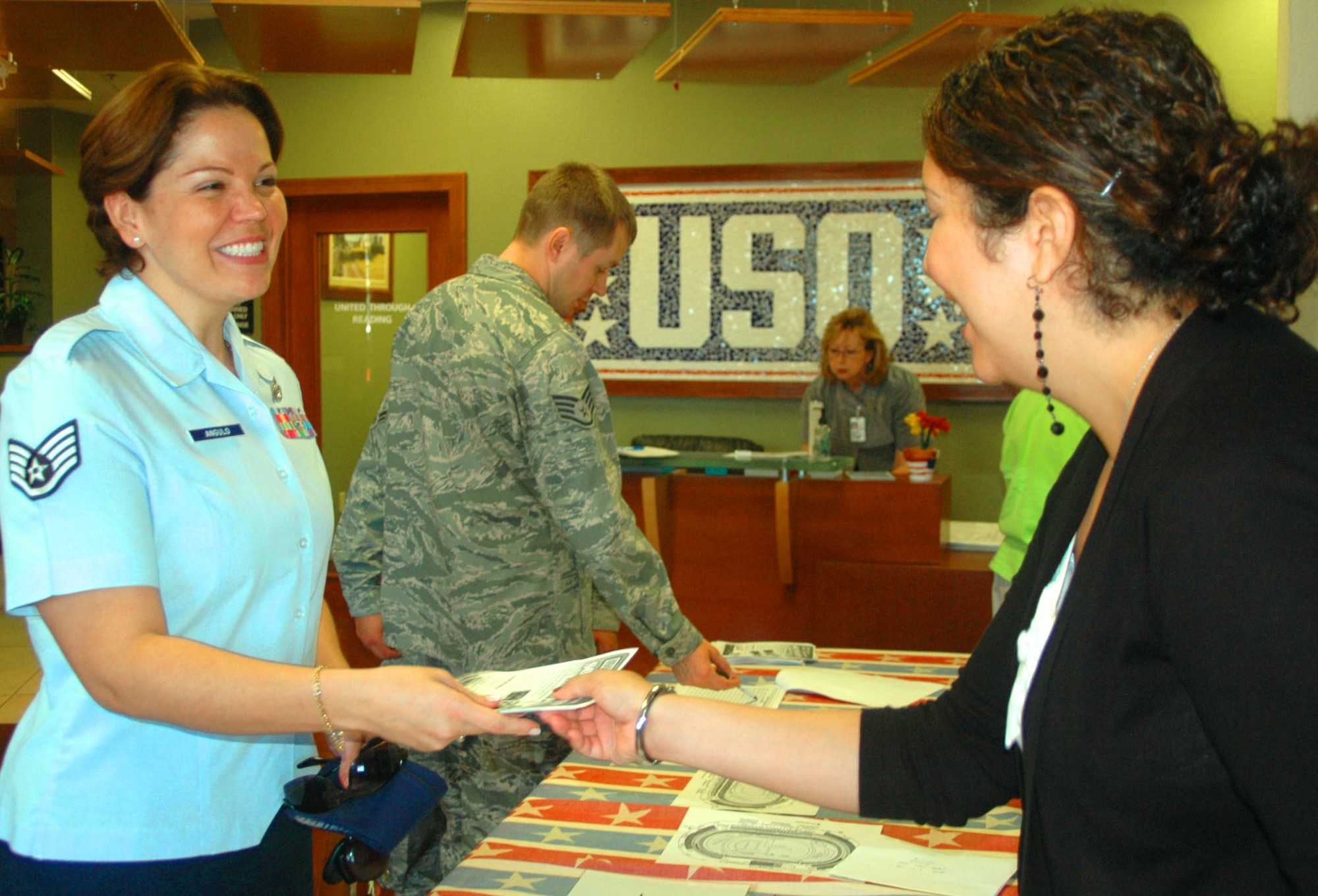 USO Delaware employee Yolanda Bottorf distributes free NASCAR tickets to Staff Sgt. Carolina Angula, 436th Airlift Wing Protocol Office, Sept. 20 inside the USO Community Center on Dover Air Force Base, Del. USO Delaware handed out hundreds of tickets to Airmen for the Sept. 26 sporting event at Dover International Speedway.