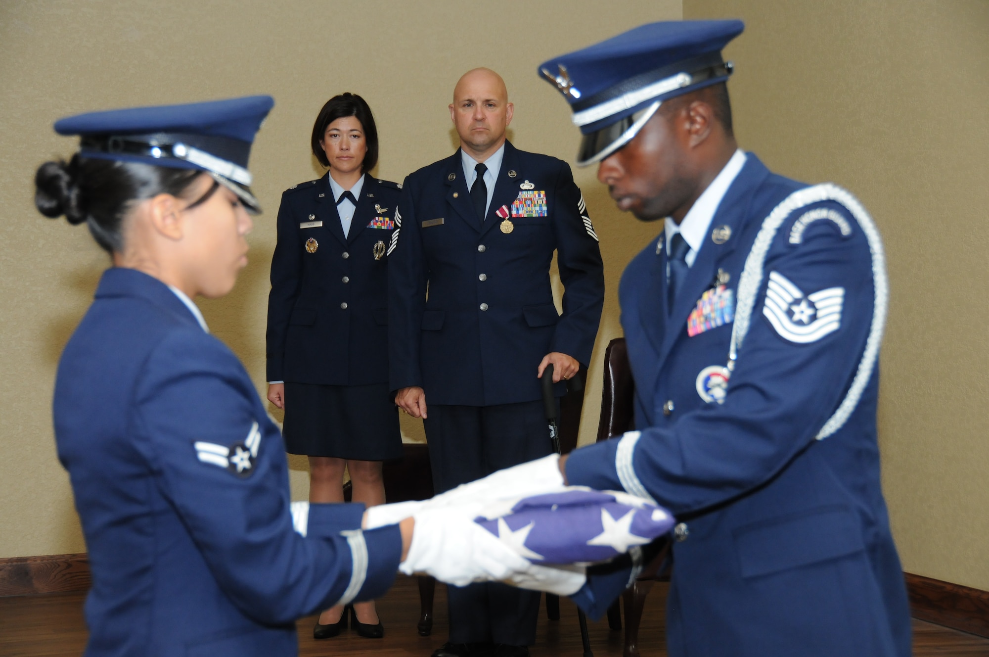 Airman 1st Class Candace Thompson and Tech. Sgt. James Shealey fold the American flag as Lt. Col. Janet Haug, 81st Training Support Squadron commander, and Chief Orslene, squadron superintendent, look on during the chief’s retirement ceremony Monday at the Bay Breeze Event Center.  (U.S. Air Force photo by Kemberly Groue)