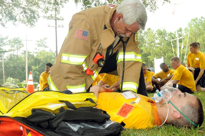 Fireman Joel Woods, assigned to the Naval Weapons Station Charleston fire department, tends to Seaman Apprentice Joshua Julian from Woodinville, Wash., after he received a simulated gunshot wound to the neck during a base-wide  active shooter exercise on Naval Weapons Station Charleston Sept. 22, 2010. The exercise was held as a joint effort between Air Force and Navy personnel to build the working relationship between both services operating as one team on Joint Base Charleston. (U.S. Navy photo/Mass Communication Specialist 1st Class Jennifer R. Hudson/released)