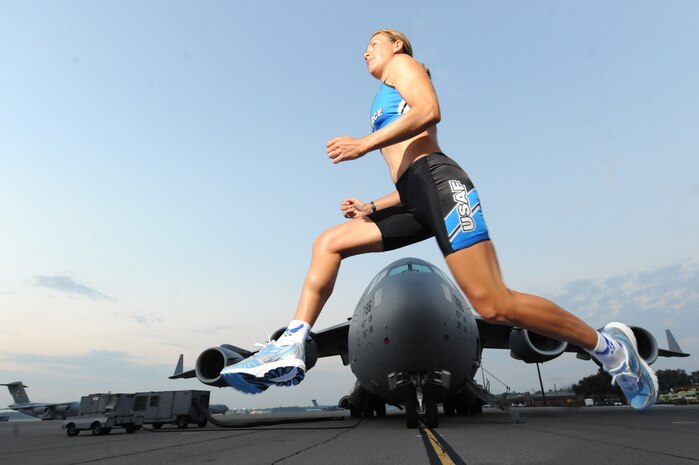 U.S. Air Force Capt. Jamie Turner, wearing her Air Force Ironman uniform, leaps into action in front of a C-17 Globemaster III on Joint Base Charleston, S.C., Sept. 21, 2010. Captain Turner is training to swim 2.4-miles through ocean waves, bike 112 miles and run a 26.2-mile marathon through challenging lava-covered terrain. Selected as one of 1,800 Ironman World Championship competitors, she will test her endurance in one of the top athletic challenges the sports world has to offer. Captain Turner is a pilot with the 315th Airlift Wing. (U.S. Air Force photo/James M. Bowman)