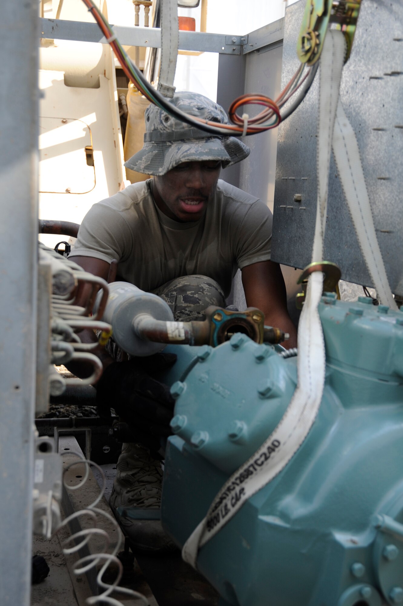 Airman 1st Class LeAndre Davis, 380th Expeditionary Civil Engineer Squadron heating ventilation and air conditioning technician guides an air conditioner compressor into place Sept. 23, 2010 at an undisclosed location in Southwest Asia. (U.S. Air Force photo/Tech. Sgt. April Wickes)