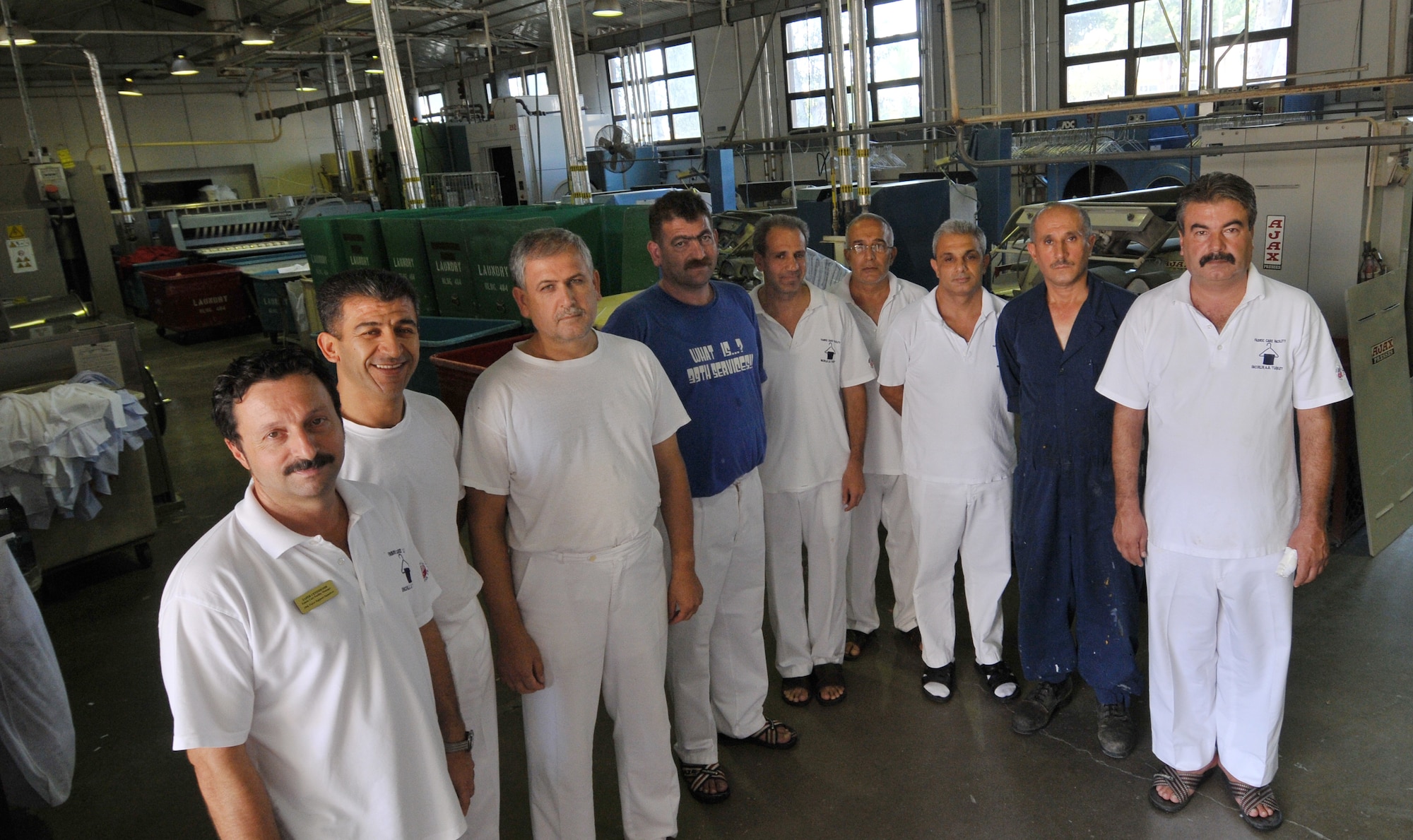 The Incirlik Fabric Care Facility host-nation employees stand for a photo inside the launder facility Sept. 21, 2010 at Incirlik Air Base, Turkey. The facility is operated by 17 Turkish host nation employees, 11 of which have been employed there for more than 20 years.  They’re responsible for the laundering and dry cleaning of roughly 50 to 60 thousand items per month and they have incorporated creative ideas making their processes more efficient and saving the Air Force more than $131,000 since 2000. (U.S. Air Force Photo/ Senior Airman Alexandre Montes)
