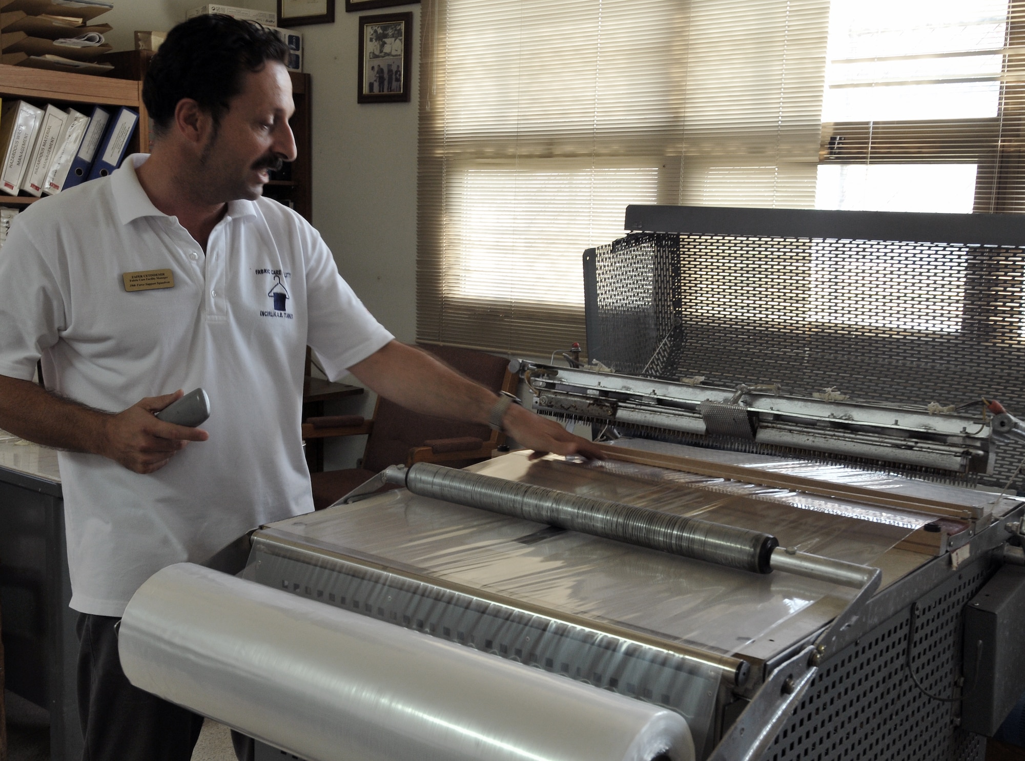 Zafar Cetindemir, Incirlik Fabric Care Facility manager, explains the operation of the garment bag machine Sept. 21, 2010 at Incirlik Air Base, Turkey. This machine was created by Bedir Tanir, Incirlik FCF mechanic, in order to cut costs and contributed to the $131,000 saved by the facility since 2000. (U.S. Air Force Photo/ Senior Airman Alexandre Montes)  