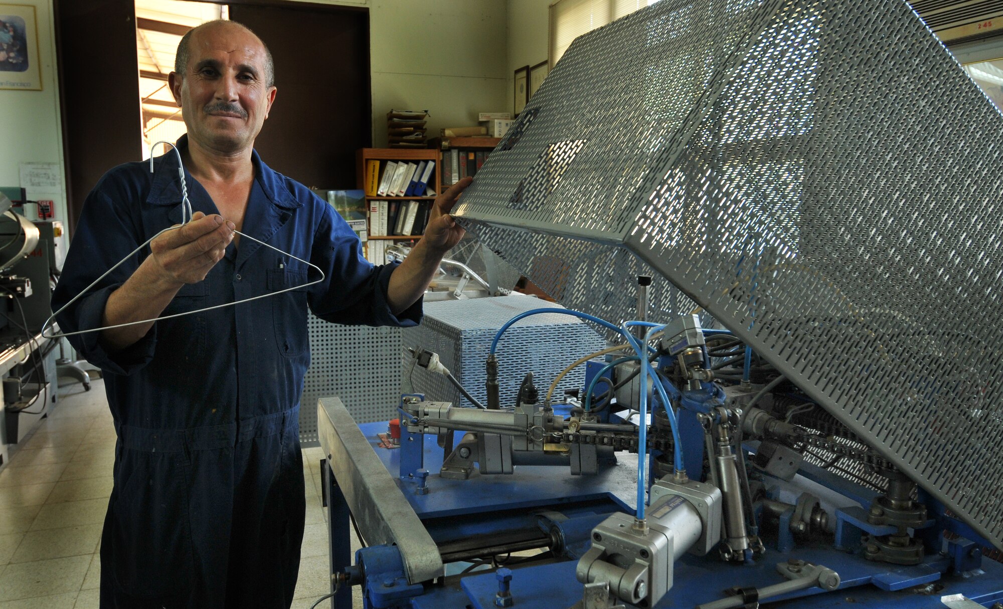 Bedir Tanir, Incirlik Fabric Care Facility mechanic, stands by the hanger-making machine he created Sept. 21, 2010 at Incirlik Air Base, Turkey. This machine was created in order to cut costs and contributed to the $131,000 saved by the facility since 2000. (U.S. Air Force Photo/ Senior Airman Alexandre Montes)