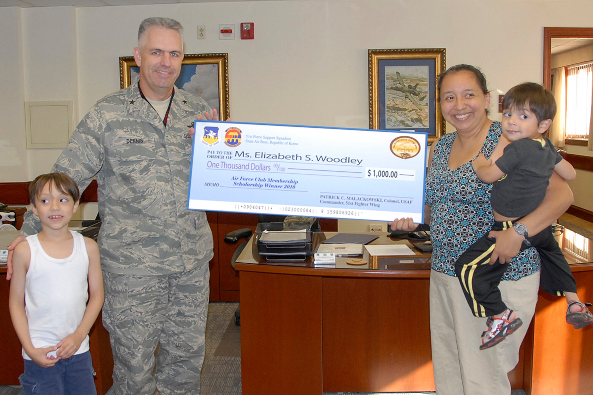 Brig. Gen. Scott Dennis, 7th Air Force vice commander, presents Elizabeth Woodley, wife of Maj. David Woodley, with a $1,000 scholarship check Sept. 23 at Osan Air Base, Republic of Korea. Mrs. Woodley received the check as the 2010 Air Force Club Membership Scholarship winner. Participants were asked to submit an essay on what the Air Force family means to them and Mrs. Woodley's essay was chosen as the best among those submitted. (U.S. Air Force photo/Staff Sgt. Eunique Stevens)