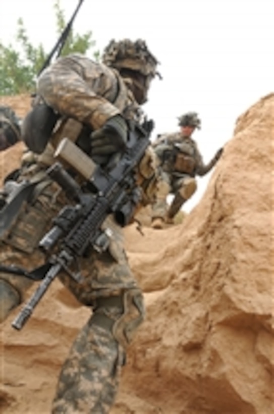 U.S. Army Cpl. Christopher Kuntor, of the 1st Battalion, 4th Infantry Regiment, helps Spc. Charles Brooks (right) into a riverbed during a presence patrol in the Zabul province of Afghanistan on Sept. 14, 2010.  