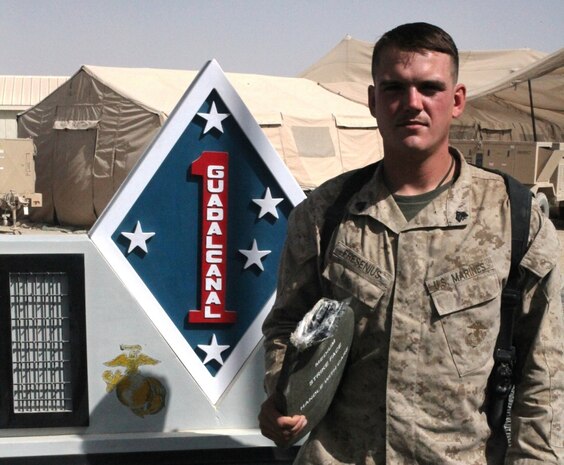 Sergeant David Fresenius, an assistant team leader with 3rd Platoon, Company B, 1st Reconnaissance Battalion, holds the protective Sapi plate that saved his life, in front of the 1st Marine Division (Forward) Memorial monument, Sept. 24. The 23-year-old from Westminster, Calif., was hit in the top of his back’s plate during a small arms fire engagement in Trek Nawa, on June 21, 2010.  The round lodged in his protective gear, just millimeters away from hitting his upper spine.  After his corpsman attended to the wound, that left a baseball-sized welt in his upper back, a very lucky and determined Fresenius re-donned his gear, and got back in the engagement with the Taliban that lasted just over an hour. “It felt like I had been hit with a sledge hammer,” Fresenius said.  “Once I realized I was okay, my only thoughts were to get back to the fight – to get back with my men.”