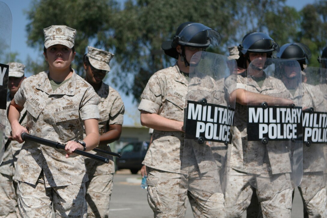 Lance Cpl. Liza Medina, a participant with the Security Augment Force training course here, prepares to move out of formation during the riot control and defensive tactics procedures training Sept. 24. Some of the participants donned shields and helmets, while others held batons.