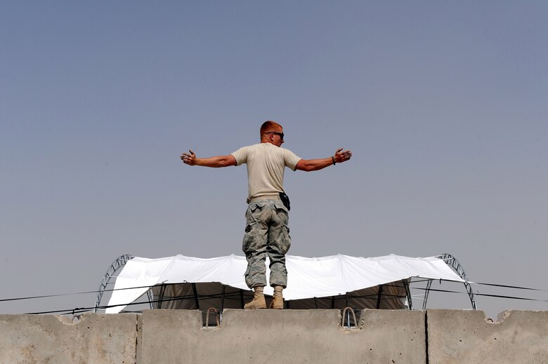 Staff Sgt. Daniel Wissmann signals to Airmen in forklifts to pull a canopy over a metal frame for an F/A-18 Hornet sun shade Sept. 24, 2010, at Kandahar Airfield, Afghanistan.  Sergeant Wissmann is a structural journeyman for the 777th Expeditionary Prime Beef Squadron and hails from Schertz, Texas. (U.S. Air Force photo by Tech. Sgt. Chad Chisholm/Released)