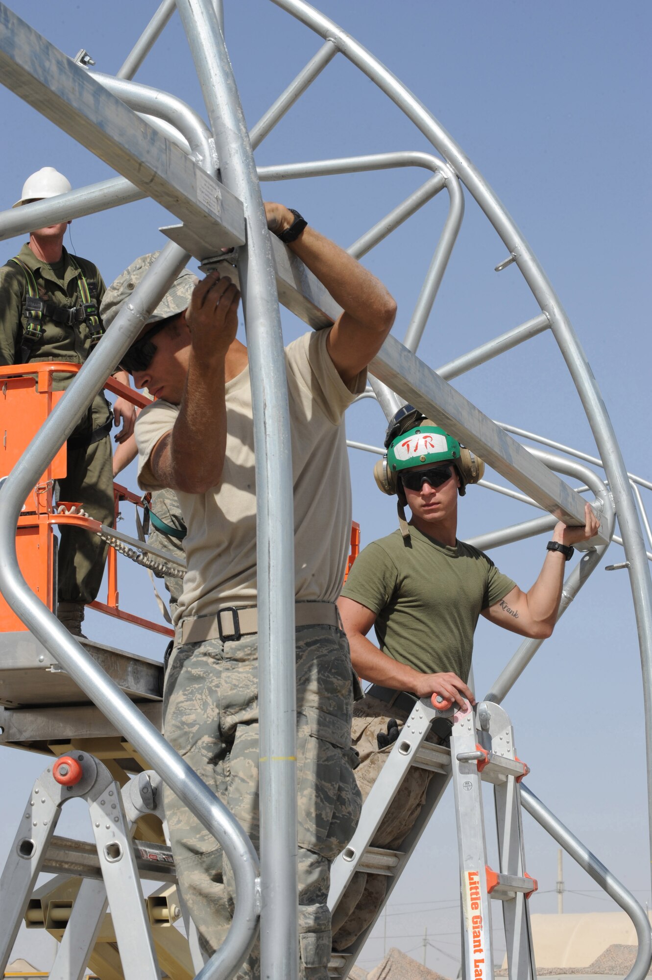 Airmen and Marines install a square tube into a metal frame Sept. 23, 2010, at Kandahar Airfield, Afghanistan.  Airmen from the 777th Expeditionary Prime Beef Squadron built F/A-18 Hornet sun shades for the 232nd Marine Fighter Attack Squadron.  (U.S. Air Force photo by Tech. Sgt. Chad Chisholm/Released)