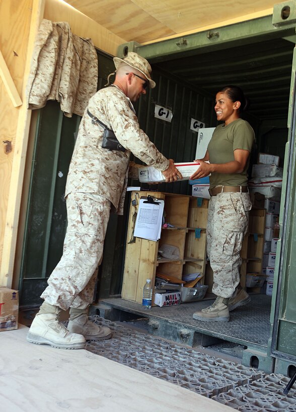 Cpl. Erica Lila, a switchboard operator with Headquarters Battalion, 1st Marine Division (Forward), gives Petty Officer 1st Class Boyd Lewis, a division religious program specialist with Headquarters Bn., 1st Marines Division (Fwd), his mail at Camp Leatherneck, Afghanistan, Sept. 26, 2010.  Care packages and letter-writing are just a few forms of keeping in touch with deployed family members and friends.