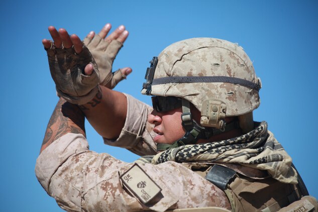 Corporal Maulalo Cortez, a rifleman from Company G, 2nd Battalion, 4th Marine Regiment, makes signals to other team members during convoy operations live-fire training here Sept. 27 at Combat Center Range 220.  The Combat Center’s Advisor Training Group trains Marines like Cortez to get them prepared to train Afghan forces. (Photo by: Lance Cpl. M. C. Nerl)::r::::n::