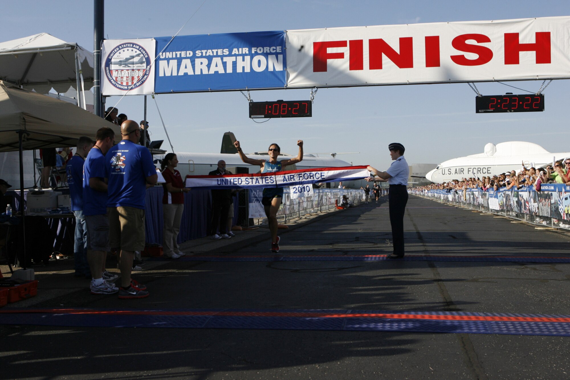 Capt. Ben Payne, 34th Special Operations Squadron pilot, center, crosses an Air Force banner held by Lt. Gen. Janet Wolfenbarger, Air Force Material Command vice-commander, right, and an unidentified volunteer during the 2010 Air Force Marathon at Wright-Patterson Air Force Base, Ohio, Sept. 18. Captain Payne finished first in the men's half marathon. (Courtesy photo) 
