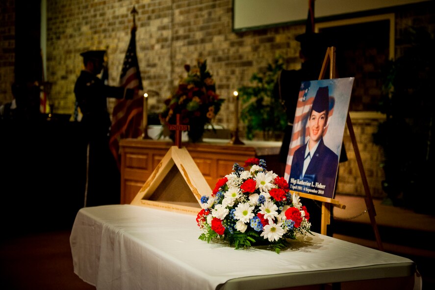 MOODY AIR FORCE BASE, Ga. -- As members of the Moody Air Force Base Honor Guard post the colors, a display honoring Staff Sgt. Katherine Fisher sits during a memorial service at the Base Chapel Sept. 22. Sergeant Fisher was assigned to the 23rd Maintenance Operations Squadron. Members from her unit and friends from on and off base attended the service to celebrate her life. (U.S. Air Force photo/Senior Airman Jamal D. Sutter)