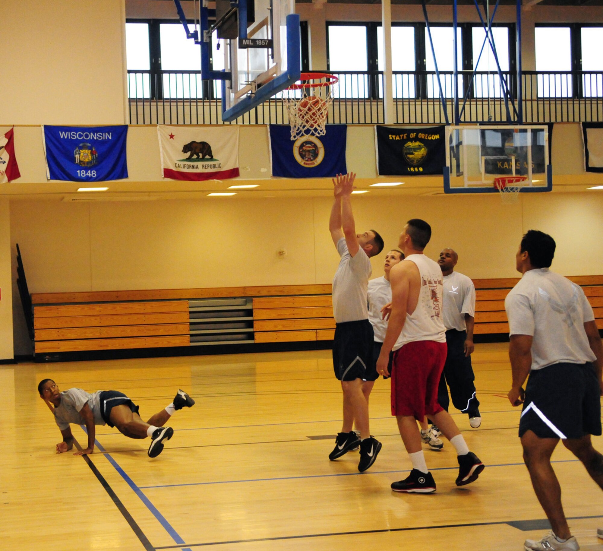 RAF MILDENHALL, England -- Tevell Serrano, 488th Intelligence Squadron, takes a tumble as David Stollings, 100th Air Refueling Wing (Team 2) reaches up to catch the ball during the 3-on-3 basketball game at the Hardstand Fitness Center for Wing Sports Day Sept. 24. Other events that day included volleyball, tug-of-war, bowling and ultimate football. (U.S. Air Force photo/Karen Abeyasekere)